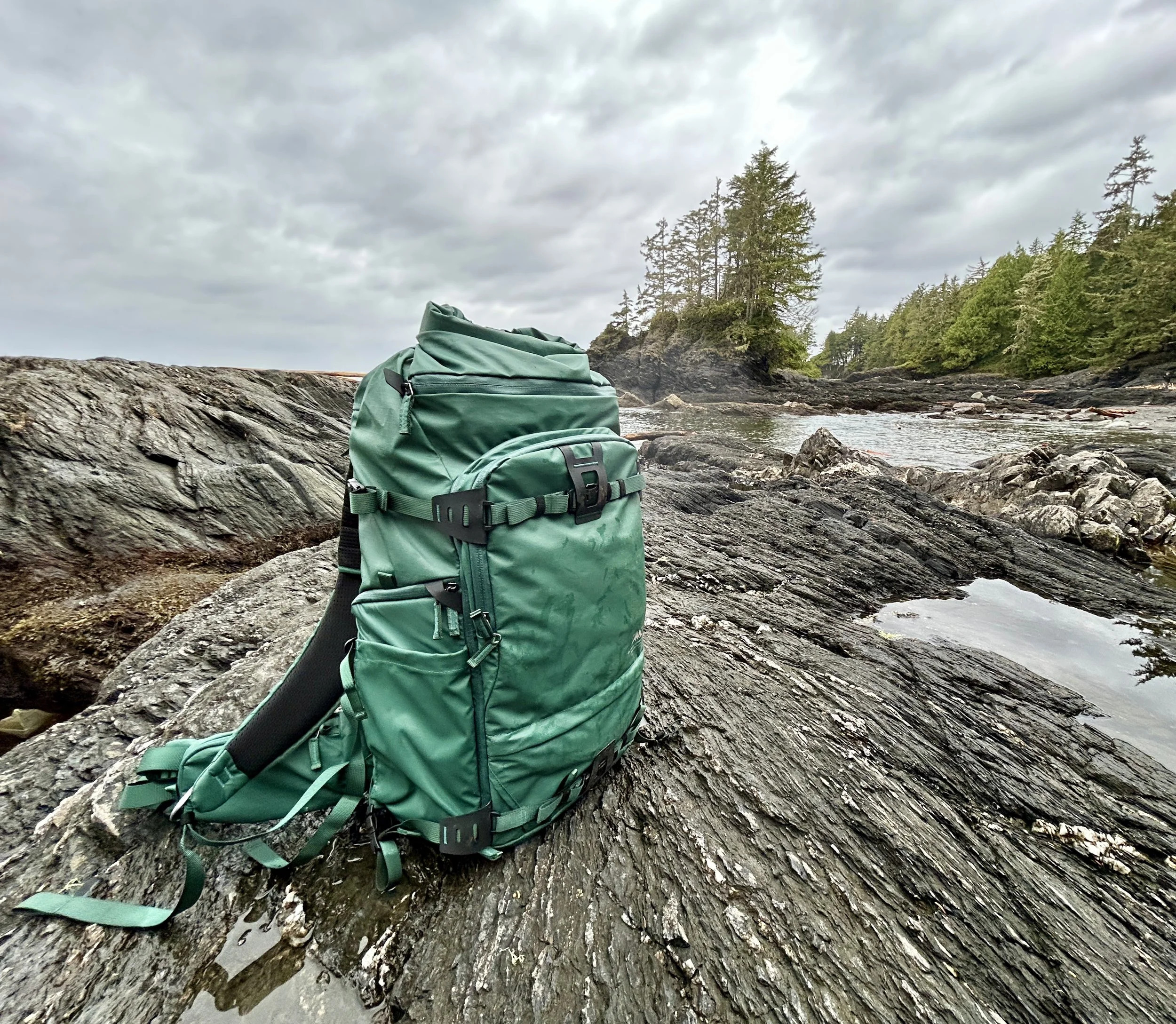 Tenzing backpack in green sitting on rocks at the coast